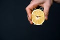 A man& x27;s hand holds a cut lemon, stylized as an alarm clock.
