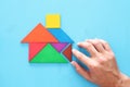 man& x27;s hand pointing at house made from tangram puzzle over wooden table. Royalty Free Stock Photo