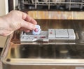 a man& x27;s hand puts a tablet of detergent in the tray for washing dishes in the dishwasher Royalty Free Stock Photo