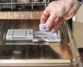 a man& x27;s hand puts a tablet of detergent in the tray for washing dishes in the dishwasher Royalty Free Stock Photo