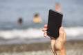 Man's hand with smartphone against the sea and pebble beach. Close-up Royalty Free Stock Photo