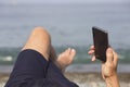 Man& x27;s hand with smartphone against the sea and pebble beach. Close-up Royalty Free Stock Photo