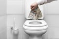 a man& x27;s hand throws American dollars into the toilet. financial crisis and inflation. falling macro indicators , ruin Royalty Free Stock Photo