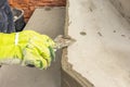 Man's hand in work gloves leveling the surface of a step before laying paving. The man wipes the masonry glue with a