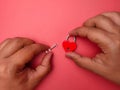 a man& x27;s hands attach a key to a heart shaped red piece