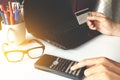 Man's hands holding a credit card over laptop and using calculat Royalty Free Stock Photo