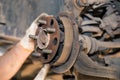 The man's hands remove the worn and rusted brake pads from the rear wheel.