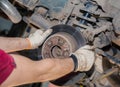 The man& x27;s hands remove the worn and rusty rear brake disc.