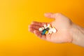 Man& x27;s palm holds a handful of different multicolored pills, capsules and drops. Yellow background. Health care Royalty Free Stock Photo