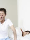 Man Yawning By Woman Sleeping In Bed Royalty Free Stock Photo