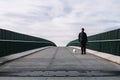 Man 45-50 years old walking his Andalusian Bodeguero Buzzard dog across a bridge Royalty Free Stock Photo