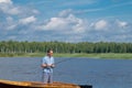 A man in yellow glasses, on a boat, holding a fishing rod and fishing in the middle of the lake, against a beautiful landscape Royalty Free Stock Photo