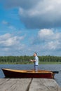 The man in the yellow glasses, the rowboat, holding a fishing rod and catches a fish on the background of the pier and the Royalty Free Stock Photo