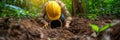 A man in a yellow helmet is digging in the dirt