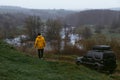 A man in a yellow jacket with his off-road vehicle. A small compact car with four-wheel drive for extreme hobbies and recreation