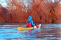 Man in a yellow kayak rowing in winter Danube river against of trees