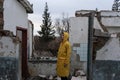 A man in a yellow protective cloak stands among the destroyed building