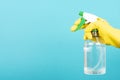 Man with yellow protective glove holding spray bottle for sanitizing cyan background. Wiping down surface concept Royalty Free Stock Photo
