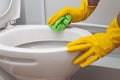 Man in yellow rubber gloves cleaning toilet with green cloth Royalty Free Stock Photo