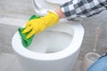 Man in yellow rubber gloves cleaning toilet seat with green cloth. Bathroom and toilet hygiene. Hand cleaning toilet bowl in Royalty Free Stock Photo