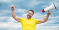 man in yellow shirt with loudhailer on sky background