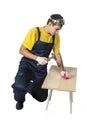 Man in the yellow shirt in overalls with a hammer hits the nail Royalty Free Stock Photo