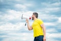 man in yellow shirt screaming in loudspeaker on sky background Royalty Free Stock Photo