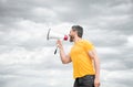 man in yellow shirt screaming in loudspeaker on sky background Royalty Free Stock Photo