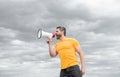 man in yellow shirt shout in megaphone on sky background. proclaim