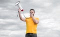 man in yellow shirt shouting in loudspeaker on sky background Royalty Free Stock Photo