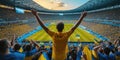 A man in a yellow shirt is standing in a stadium with his arms in the air AIG41