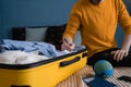 A man in a yellow sweater writes down what to take with him on a trip. Making check list of things to pack for travel