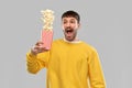 Man in yellow sweatshirt playing with popcorn