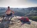 Man in yoga pose has picnic dinner in the wilderness in sunrise
