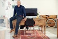 The man you want leading your team. Portrait of a casually-dressed mature man sitting on his desk in an office. Royalty Free Stock Photo