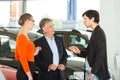 Man with young couple in car dealership Royalty Free Stock Photo