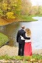 Man and young woman look at water near pond in