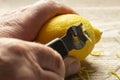 Man zesting a lemon with a lemon zester on a chopping board