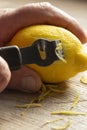 Man zesting a lemon with a lemon zester on a chopping board Royalty Free Stock Photo