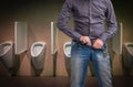 Man zip his pants up after peeing on the public toilet