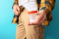 The man zips up his trousers and holds a jar of sperm in his hand. Close-up. Blue background. The concept of sperm Royalty Free Stock Photo