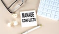 MANAGE CONFLICTS text on sticky with pen ,calculator and glasses on beige background