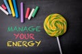 MANAGE YOUR ENERGY. Text, colored chalk crayons and lollipop on blackboard Royalty Free Stock Photo