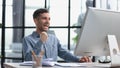 Happy businessman rejoices at success in the workplace in the office, looks up with a euphoric expression on his face.