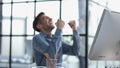 Happy businessman rejoices at success in the workplace in the office, looks up with a euphoric expression on his face.