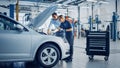 Manager Checks Data on a Tablet and Explains an Engine Breakdown to an Empowering Female Mechanic. Royalty Free Stock Photo