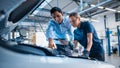 Manager Checks Tasts on a Tablet Computer and Explains an Engine Breakdown to an Female Mechanic. Royalty Free Stock Photo