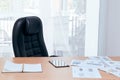 Manager desk and chair near window with note book tablet and sale document