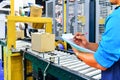 Manager engineer checking cardboard boxes on conveyor belt in distribution warehouse Royalty Free Stock Photo