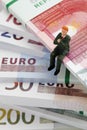 Manager figurine sitting on stack of euro notes